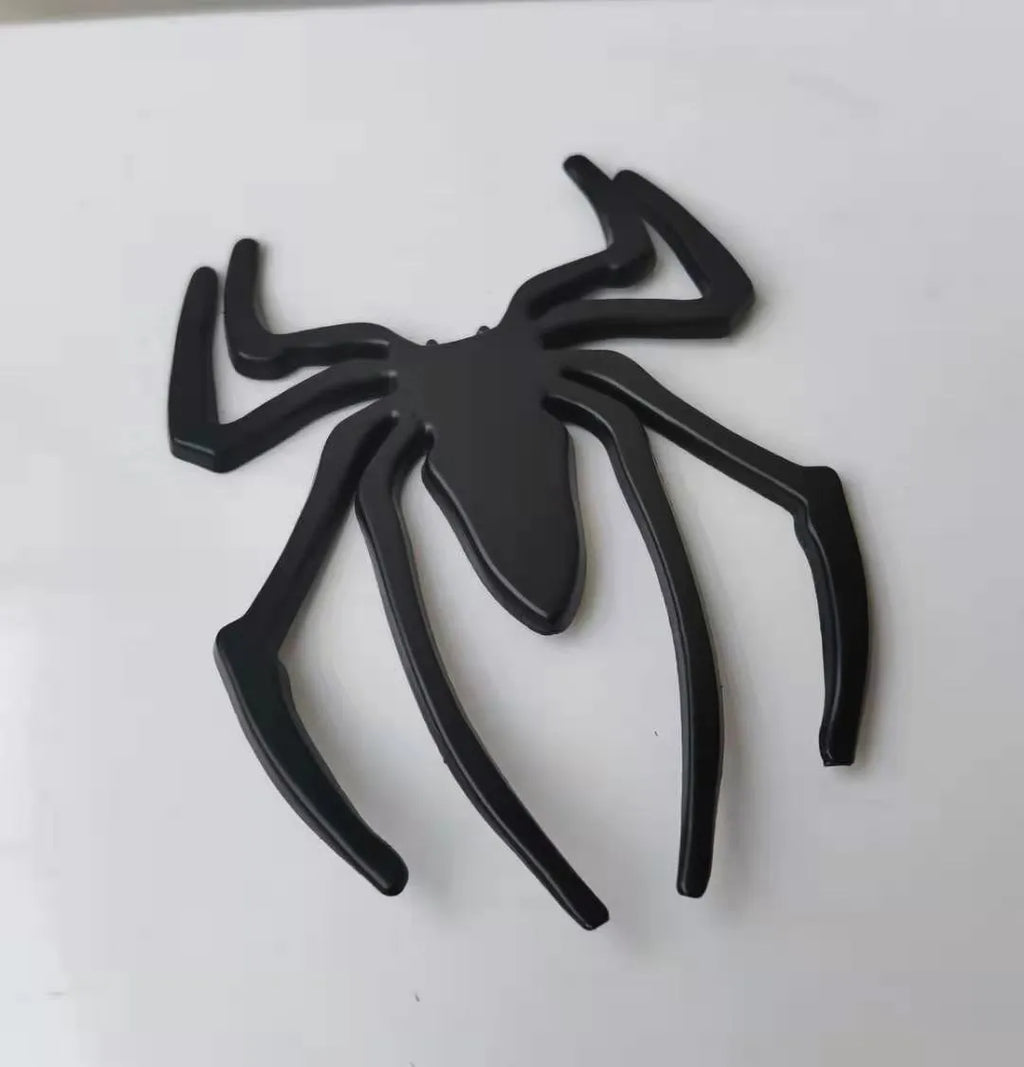 Three-dimensional metal spider bumper sticker in zinc alloy on a car bumper.