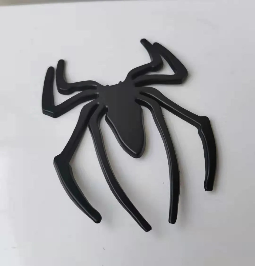 Three-dimensional metal spider bumper sticker in zinc alloy on a car bumper.