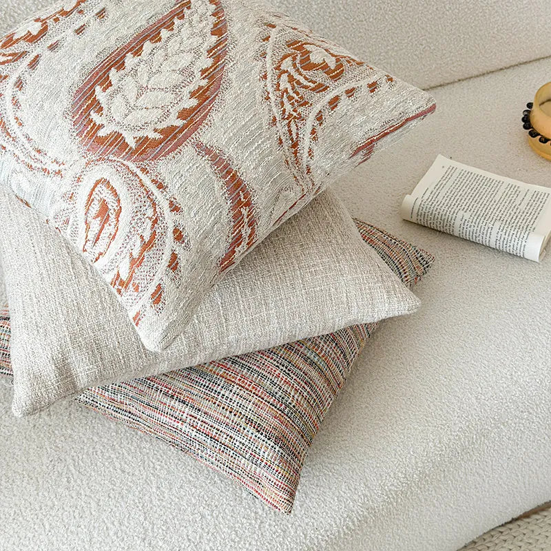 Jacquard woven paisley pattern pillow cover in amber colours on a sofa.