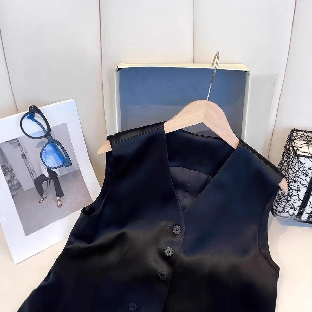 Black satin women's sleeveless vest on a hanger, showing loose fit and normal length.
