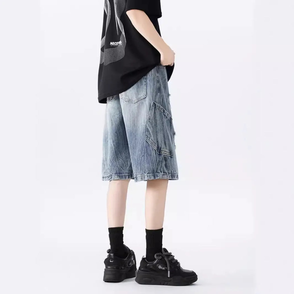 Men's loose fit distressed denim shorts with ripped knee detailing in retro style