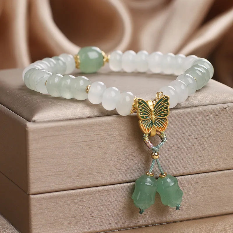 Green crystal abacus bead bracelet with butterfly charm and tassel detail, 17 cm length