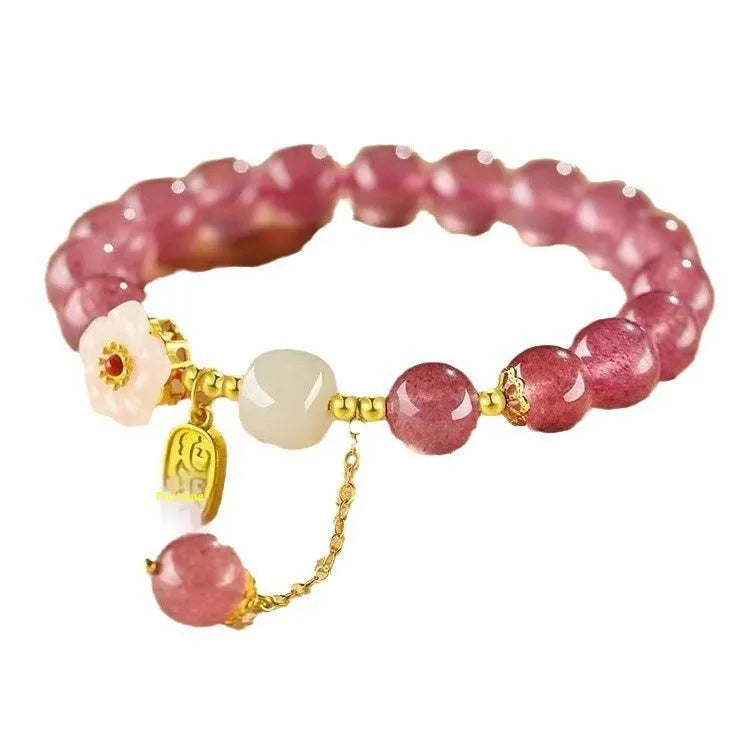 Handmade strawberry quartz crystal bracelet with peach blossom design on a wrist.