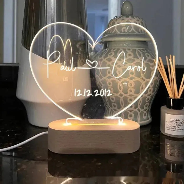 Custom acrylic night light with engraved names illuminated by LED base on bedside table