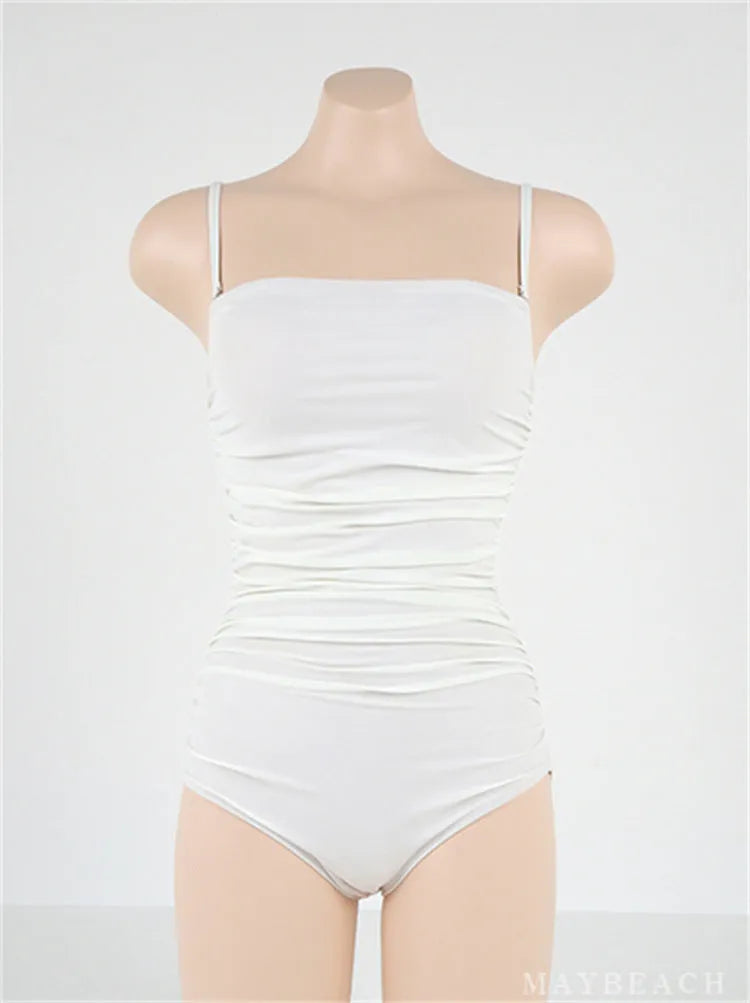 Sling style one-piece swimsuit with belly pleating in blue, white, yellow or black solid colours