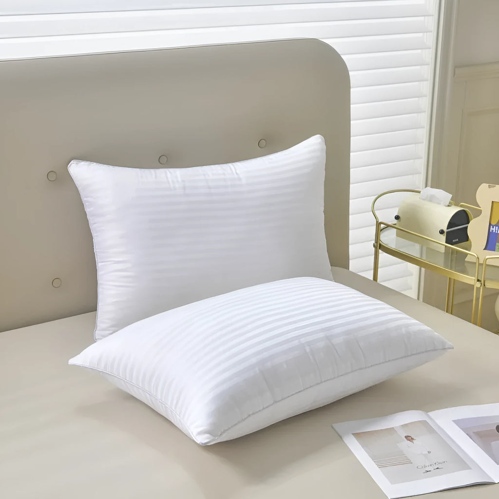 White cotton satin stripe feather pillow showing simple design on a bed.
