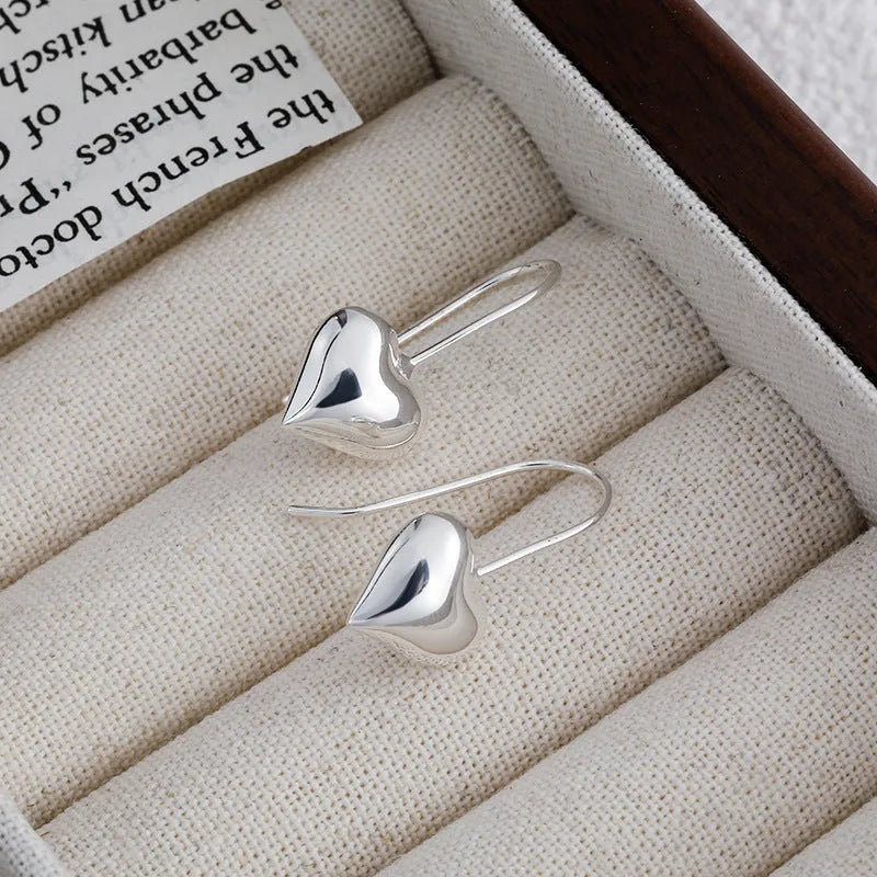 Silver-toned heart-shaped women's earrings with glossy finish and matching heart-shaped ear hooks.