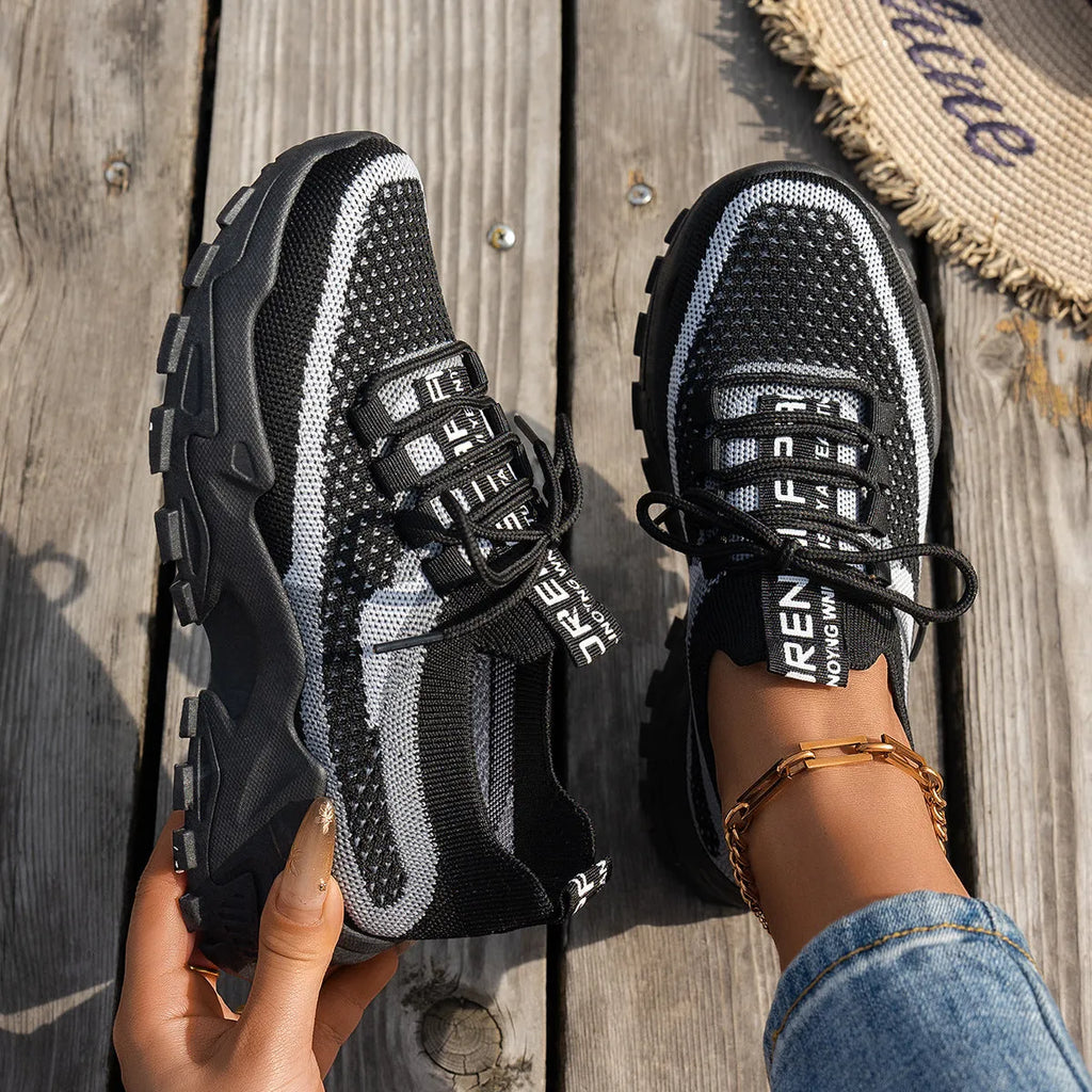 Women's Flyknit mesh lace-up sneakers in a grey colourway, showing the breathable upper and rubber sole.