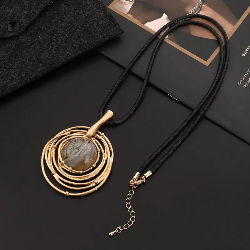 Large round gold geometric pendant on a long adjustable snakeskin rope chain necklace for sweaters