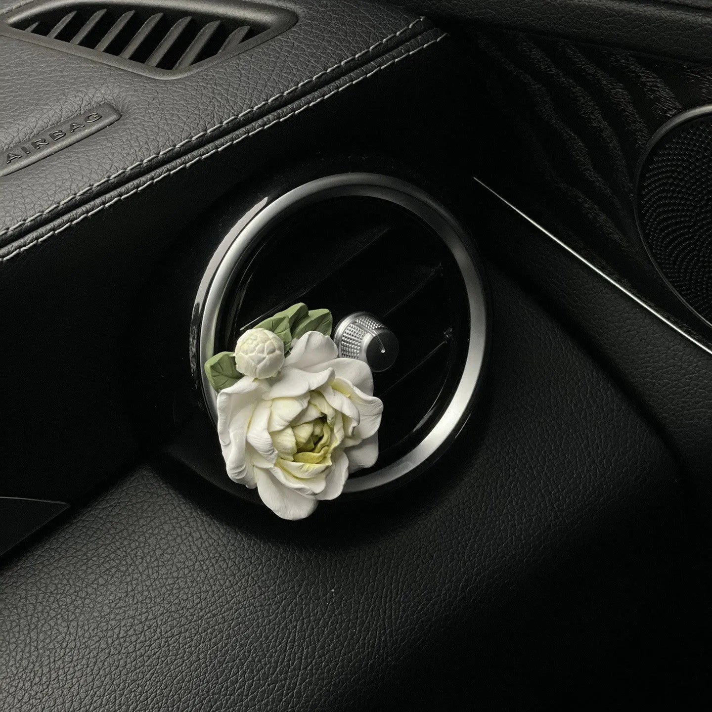 Solid jasmine car perfume diffuser clipped on a car air vent in off white or fresh green.