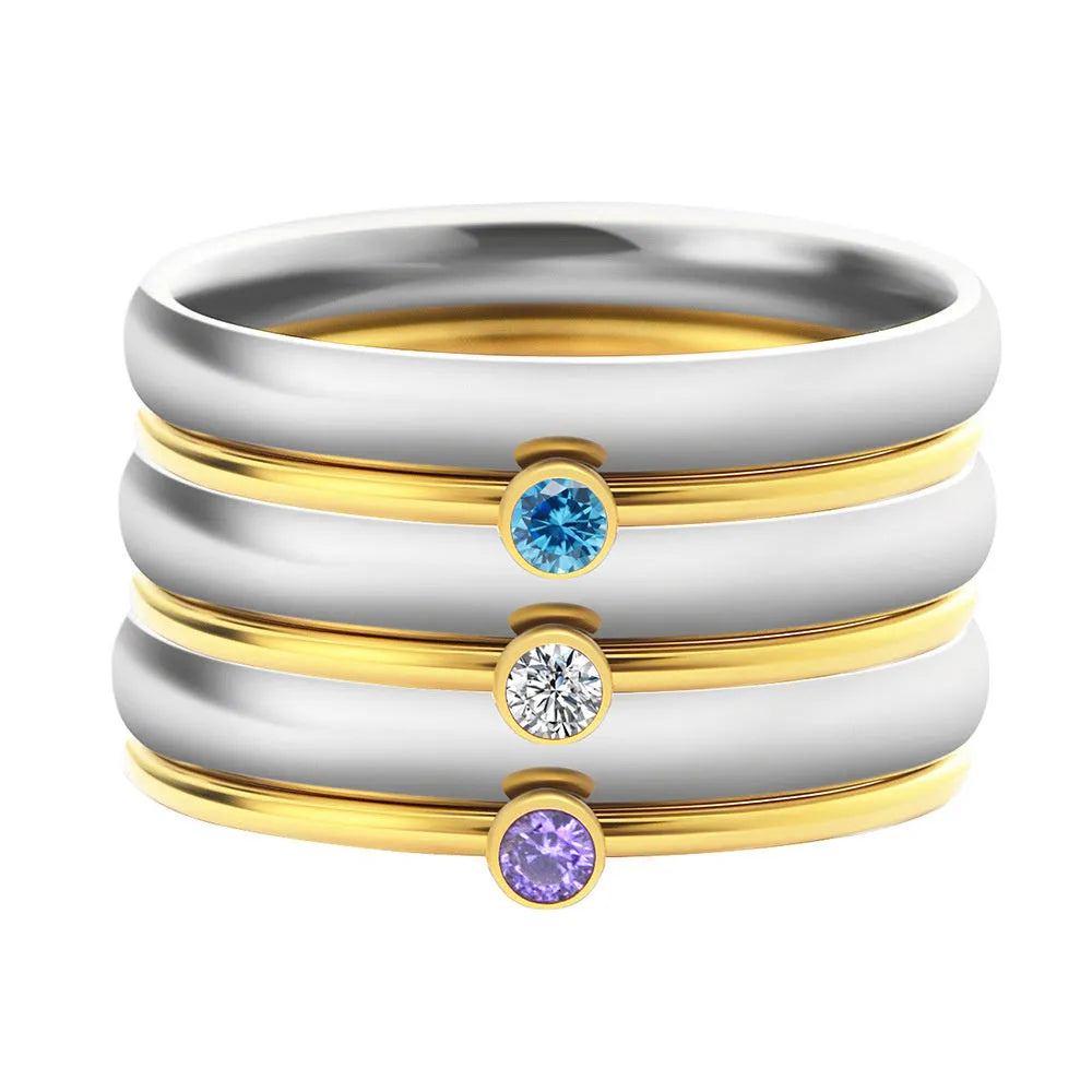 Geometric titanium steel ring with engraved design in December birthstone colour on a finger.