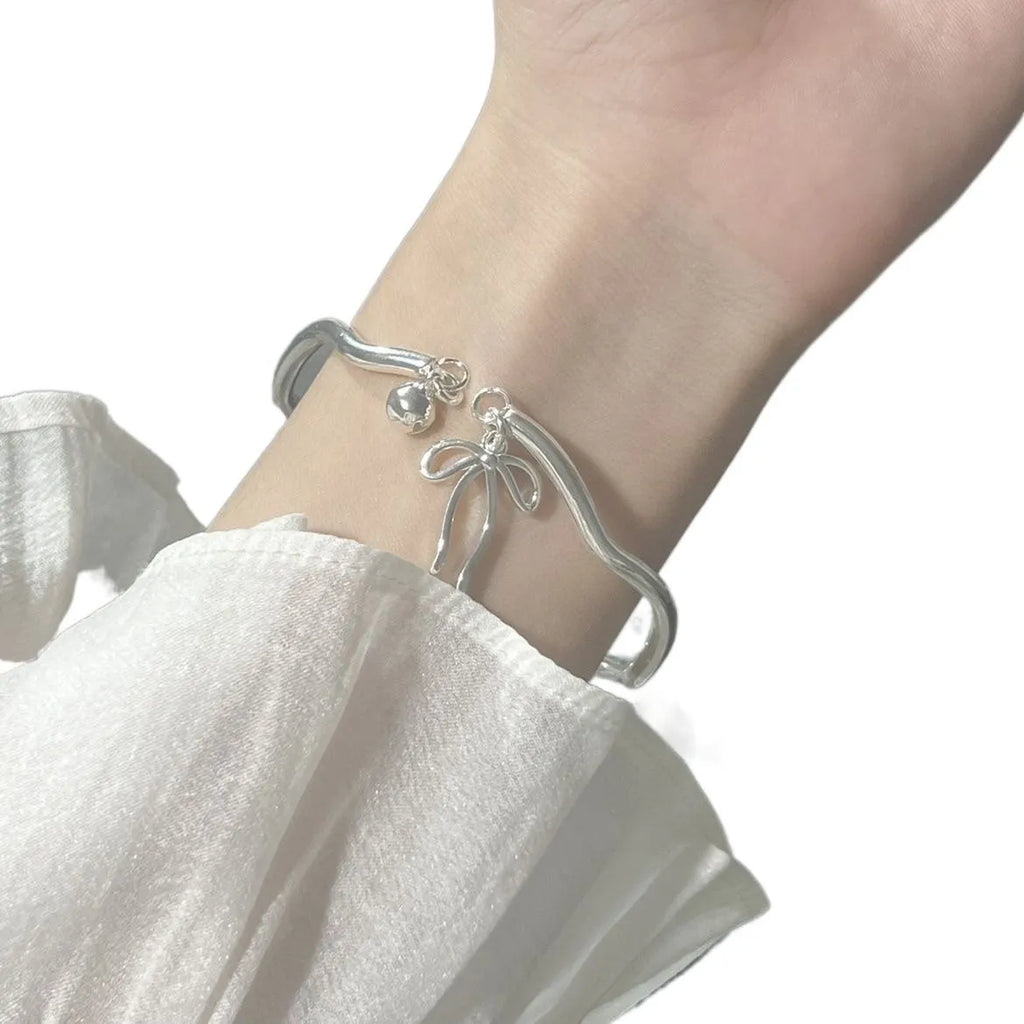 Silver bow adjustable bracelet with bell opening clasp on wrist