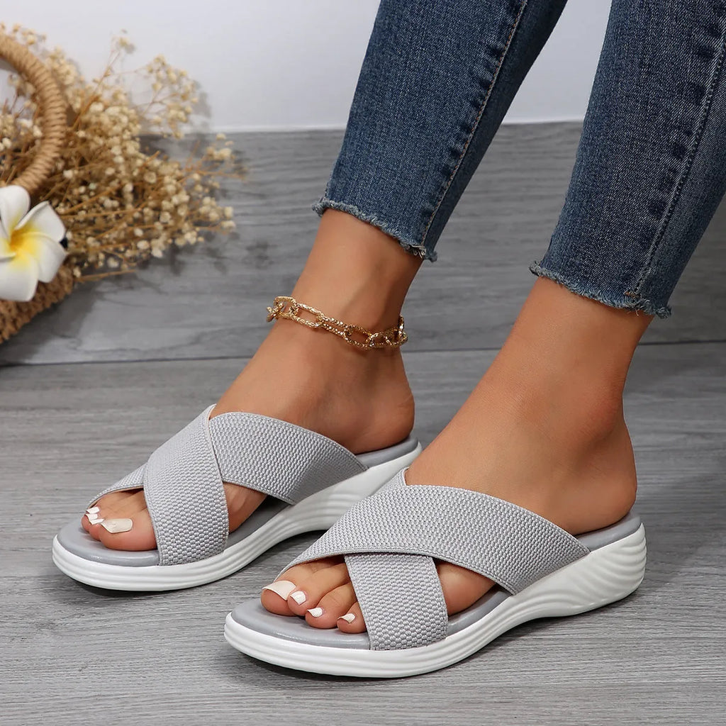 Women's black wedge peep-toe slippers with a cross-strap design and thick rubber sole.