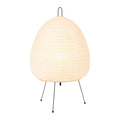 Japanese style rice paper table lamp with aluminium base on a wooden table.