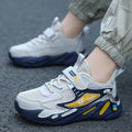 Boys sports running shoes in dark blue with a mesh upper and Velcro strap, shown on a hard ground surface.