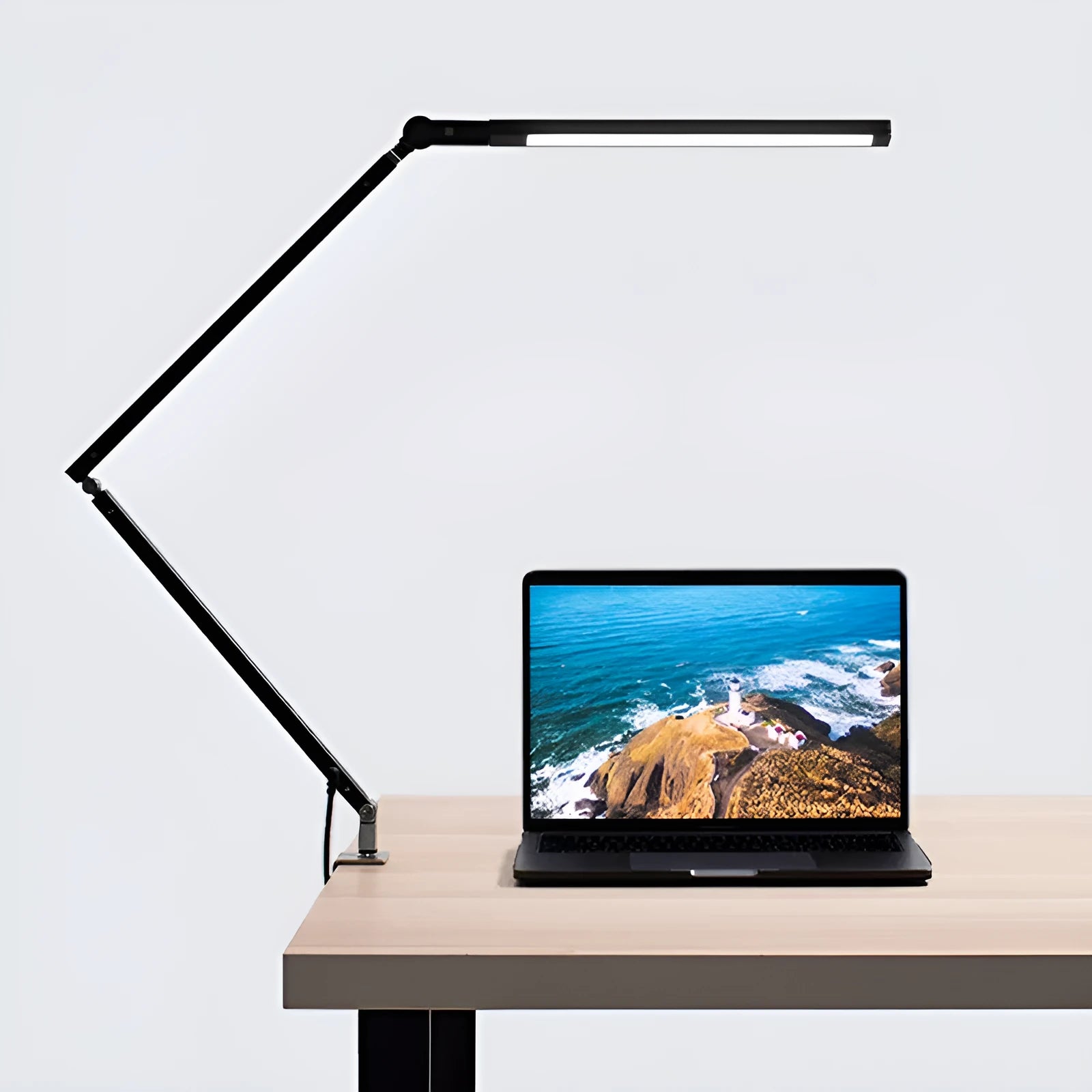 Aluminium LED desk lamp with a folding clip, remote control, and black finish on a desk.