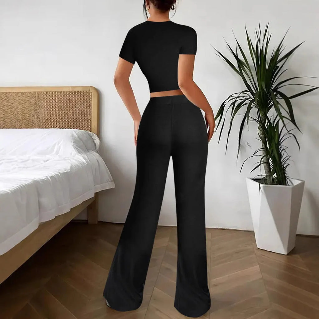 Women's black high waist trousers and short sleeve t-shirt co-ord set laid flat.