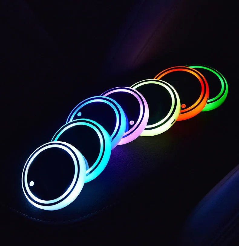 Colourful LED light-up coaster for car cup holder with USB cable on a car centre console.