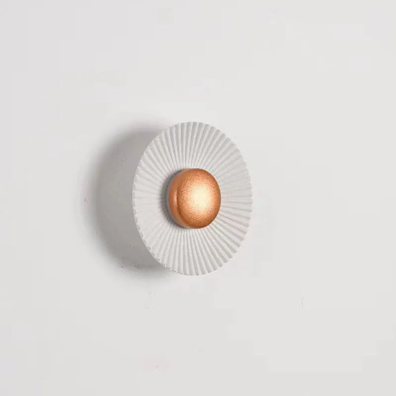 Round white and gold aluminium wall lamp mounted on a wall, LED light source visible.