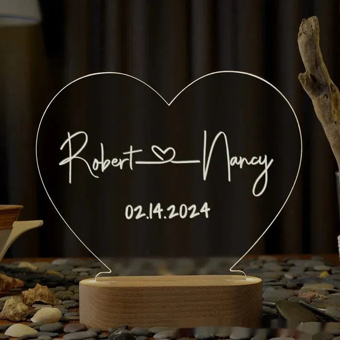 Custom acrylic night light with engraved names illuminated by LED base on bedside table