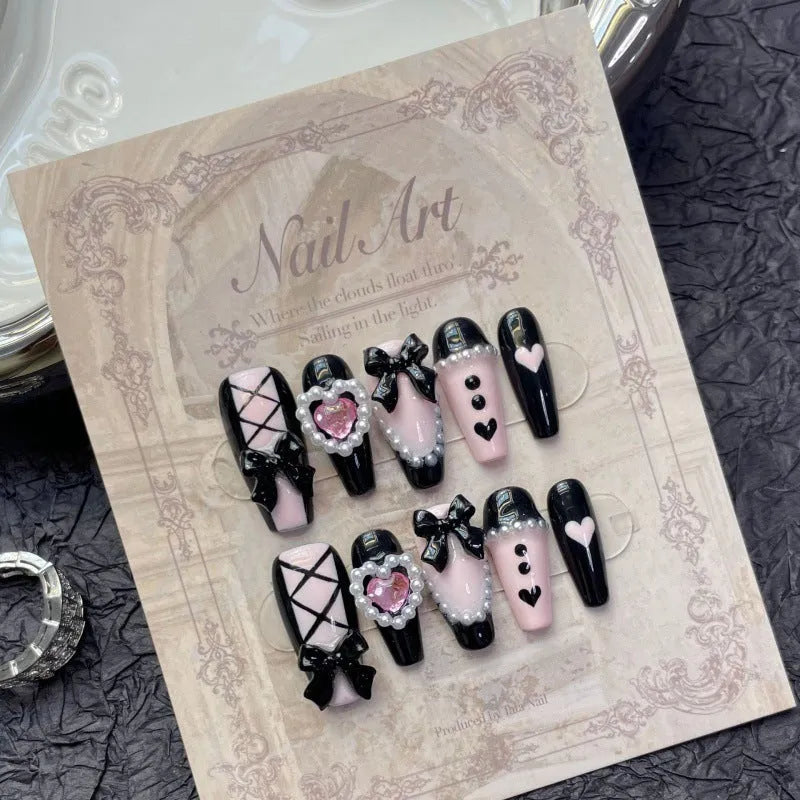 Detachable artificial nails with hand-painted black and pink heart design and cat's eye finish in four sizes